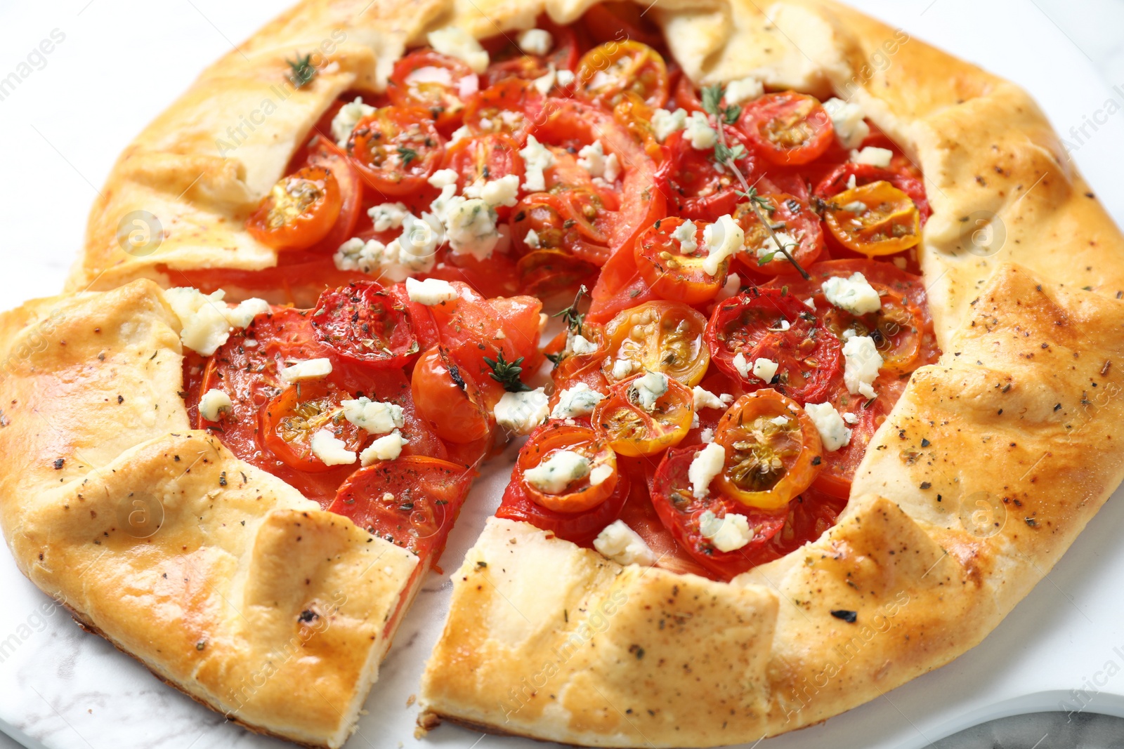 Photo of Tasty galette with tomato, thyme and cheese (Caprese galette) on white table, closeup