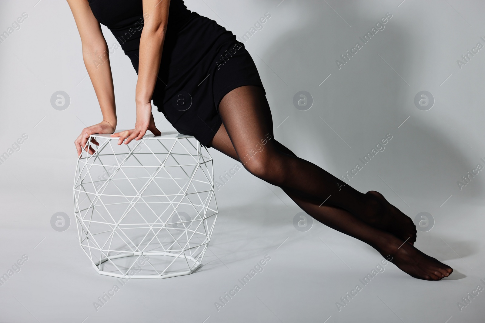 Photo of Woman with beautiful long legs wearing black tights on light background, closeup