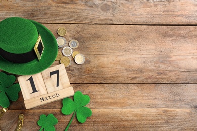 Leprechaun's hat, block calendar and St. Patrick's day decor on wooden background, flat lay. Space for text