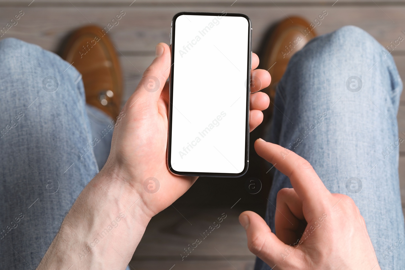 Photo of Man holding smartphone with blank screen indoors, top view. Mockup for design