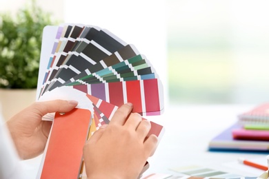 Woman with paint color palette samples on blurred background, closeup