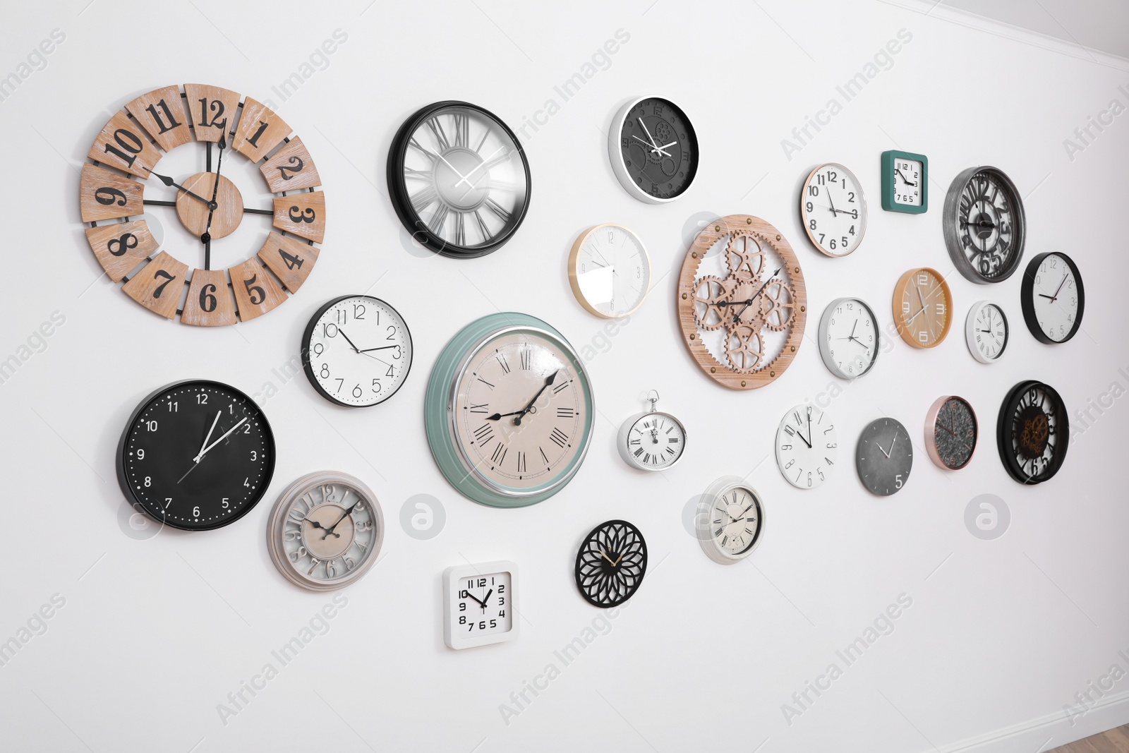 Photo of Collection of different clocks hanging on white wall