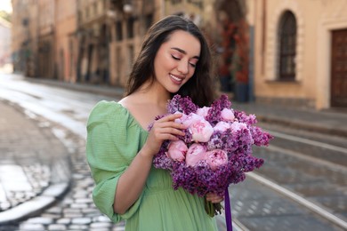 Photo of Beautiful woman with bouquet of spring flowers on city street