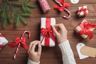 Woman wrapping Christmas gift at wooden table, top view