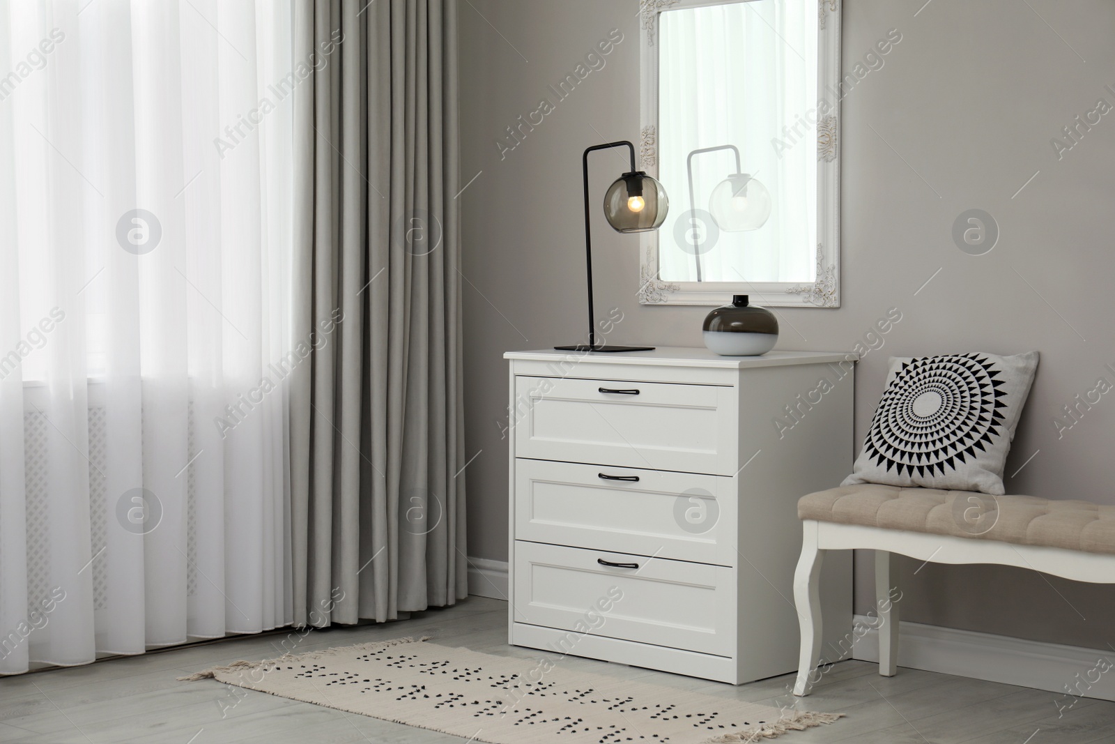 Photo of Hallway with stylish chest of drawers and mirror. Interior design