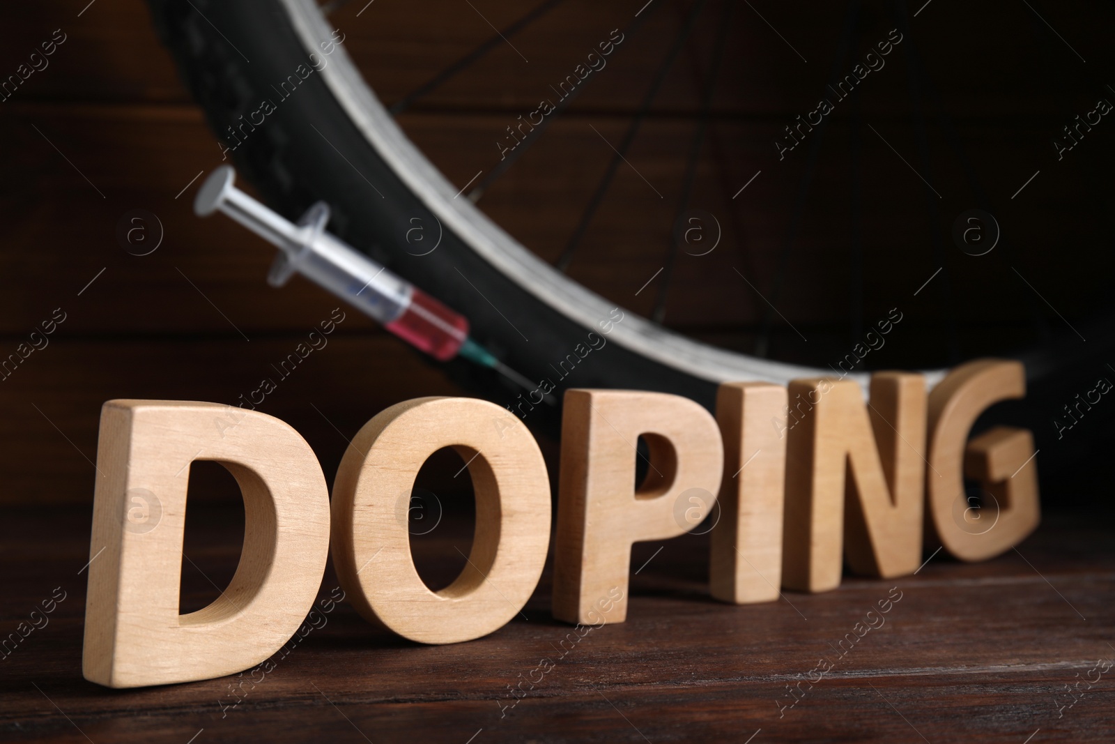 Photo of Word Doping, syringe and bicycle wheel on wooden background
