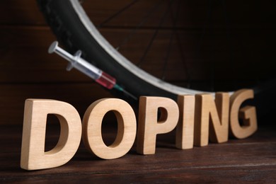 Word Doping, syringe and bicycle wheel on wooden background