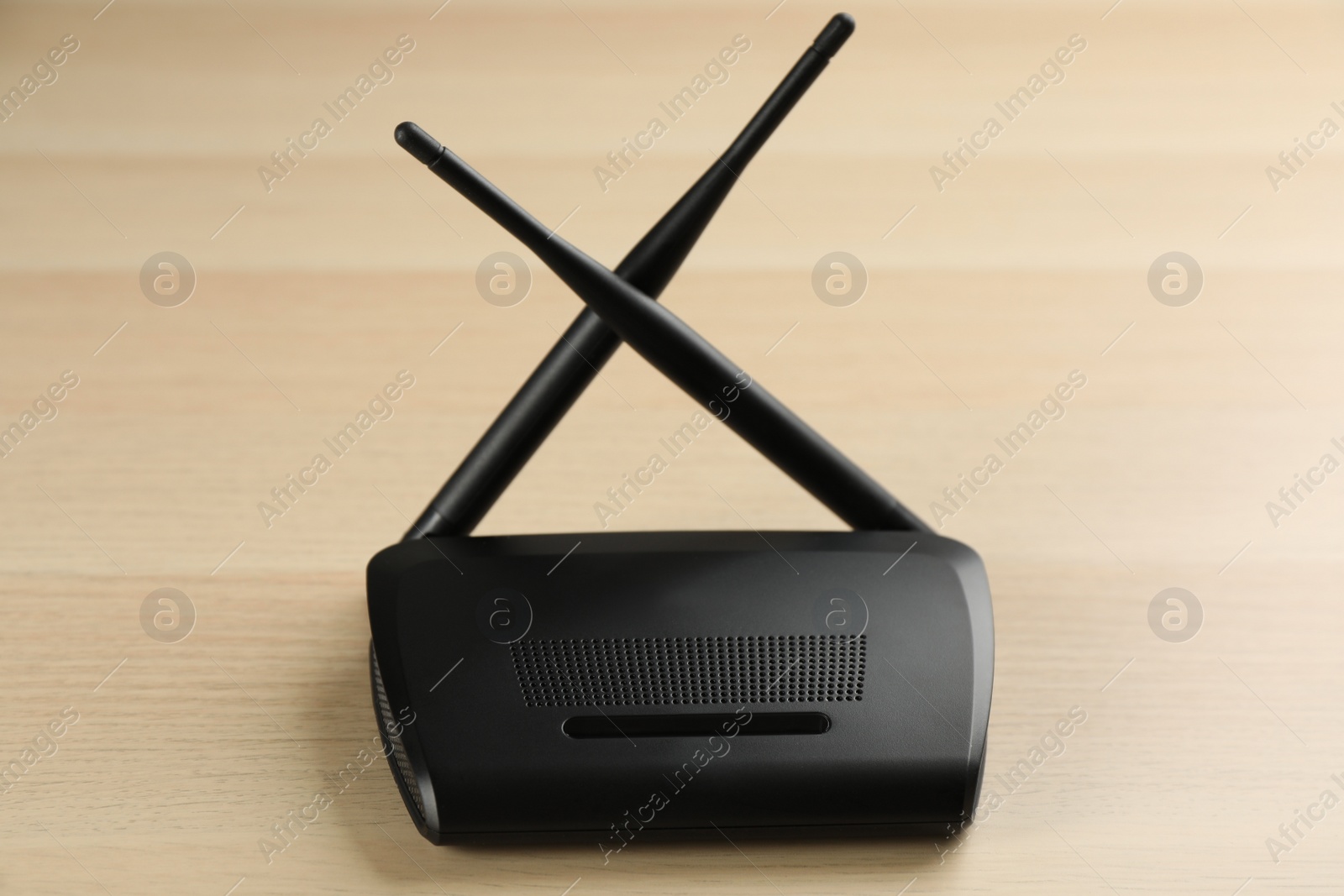 Photo of New modern Wi-Fi router on wooden background