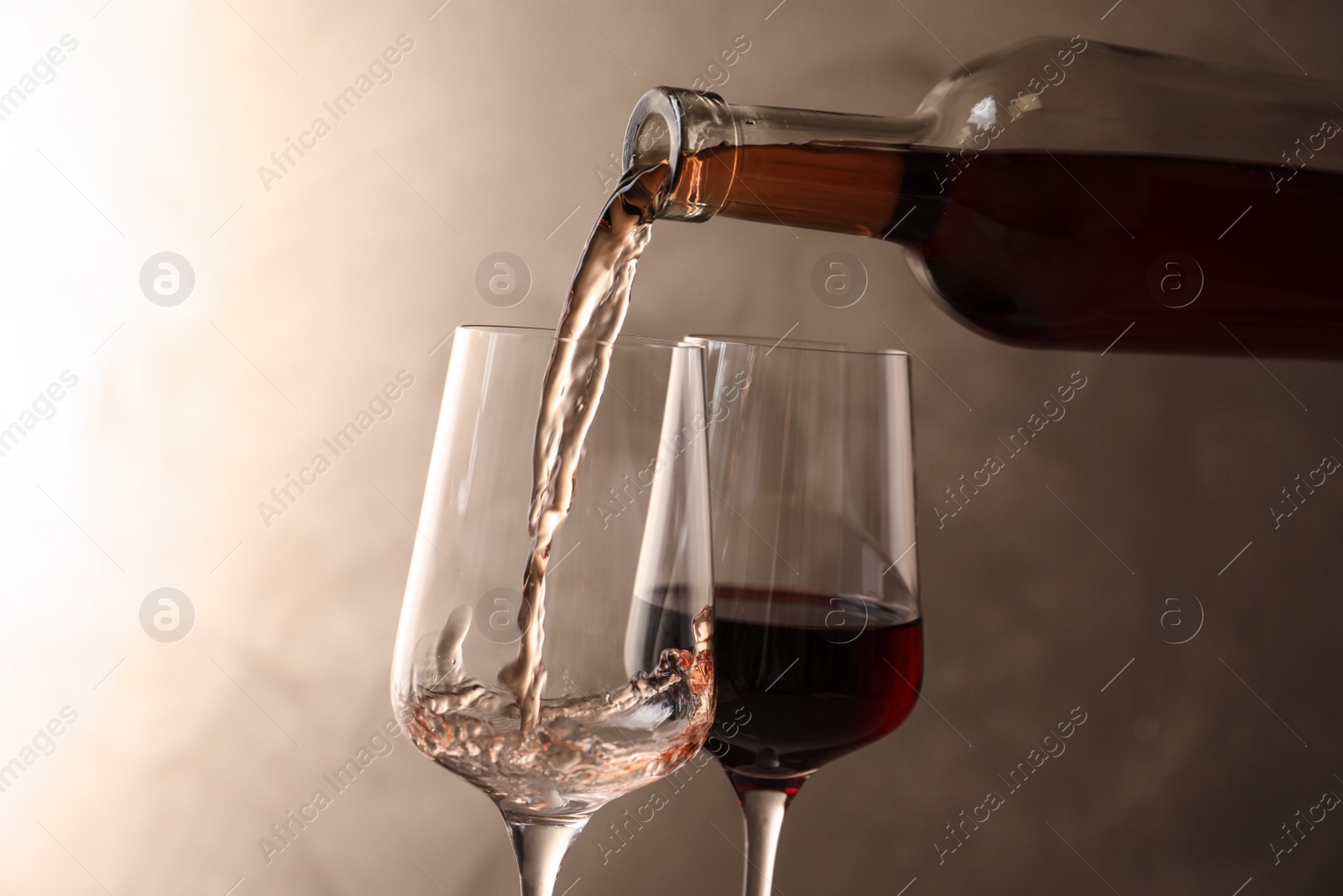 Photo of Pouring wine from bottle into glass on color background