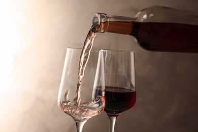 Photo of Pouring wine from bottle into glass on color background