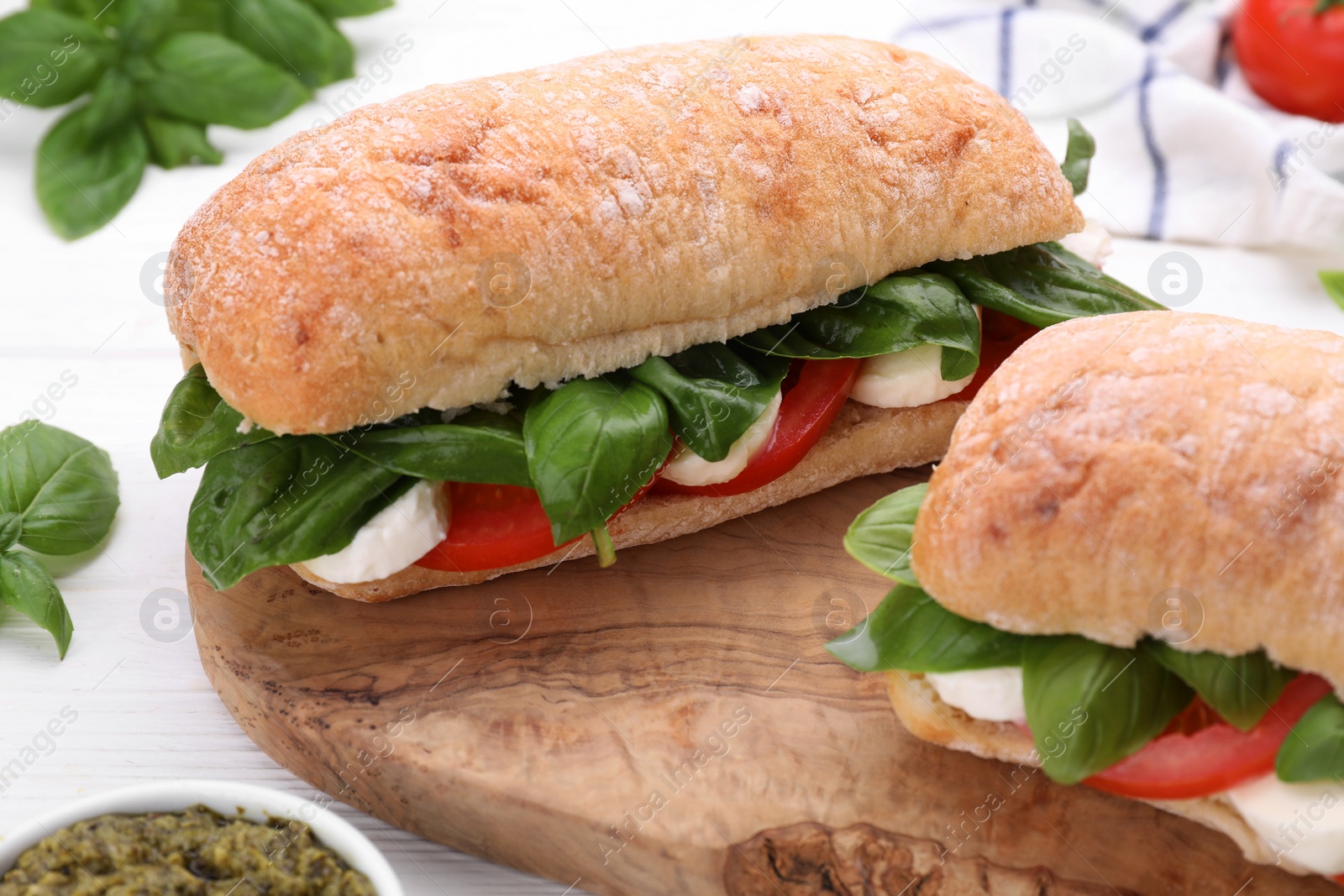 Photo of Delicious Caprese sandwiches with mozzarella, tomatoes and basil on white wooden table, closeup