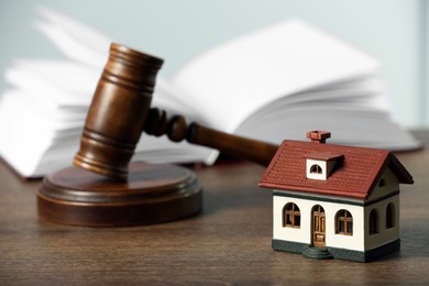 Construction and land law concepts. Judge gavel, open book with house model on wooden table
