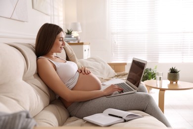 Photo of Pregnant woman working on sofa at home. Maternity leave