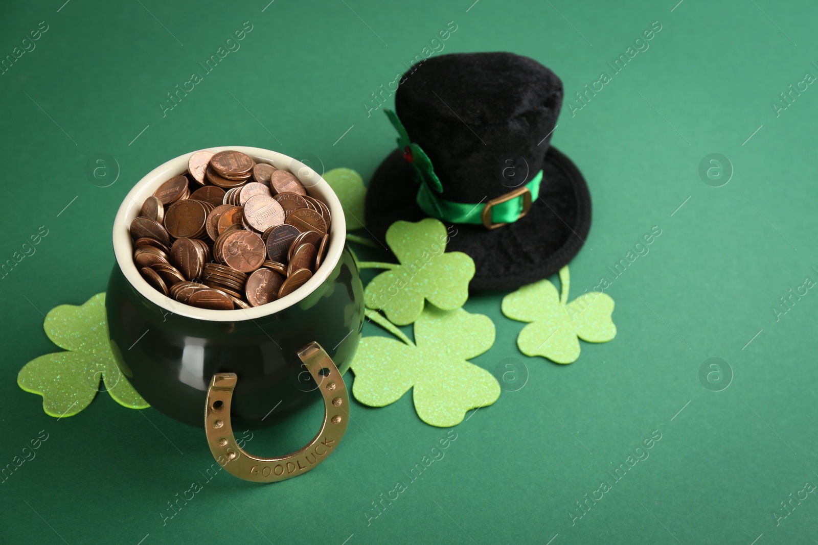 Photo of Composition with pot of gold coins and clover leaves on green background. St. Patrick's Day celebration