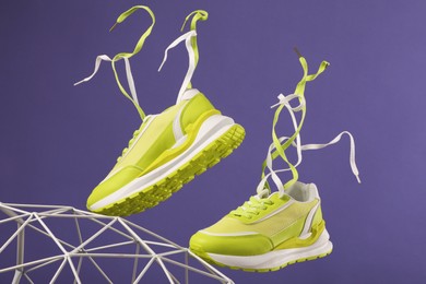 Photo of Stylish presentation of trendy sneakers on purple background