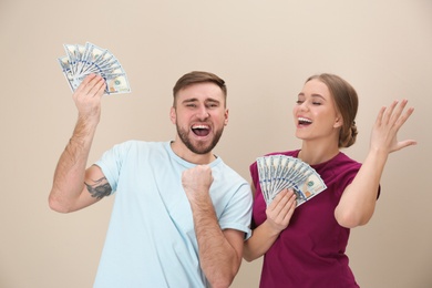 Happy young couple with money on color background