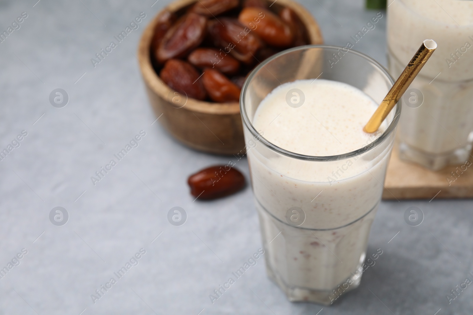 Photo of Glass of delicious date smoothie and dried fruits on light grey table, closeup. Space for text