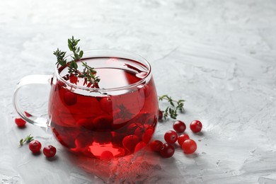 Photo of Delicious cranberry tea with thyme and berries on grey table, closeup. Space for text