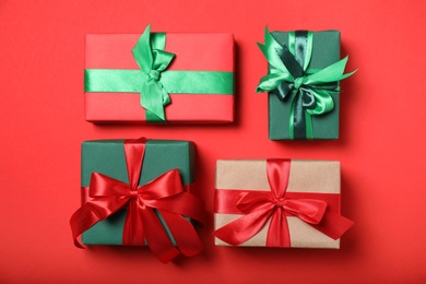 Photo of Elegant gift boxes with bows on red background, flat lay