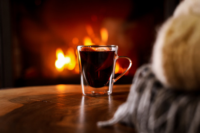 Photo of Tasty mulled wine and blurred fireplace on background