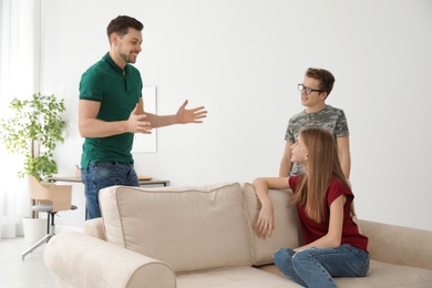 Photo of Father talking with his teenager son and daughter at home