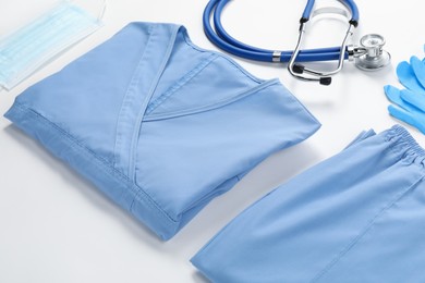 Photo of Medical uniform, mask, gloves and stethoscope on white background