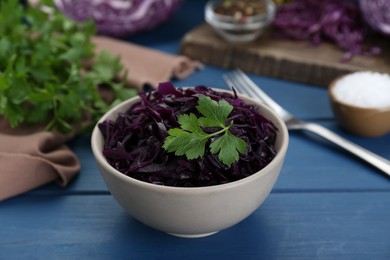 Photo of Tasty red cabbage sauerkraut with parsley on light blue wooden table