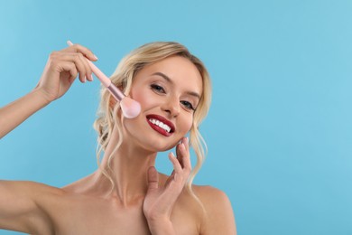 Photo of Beautiful makeup. Smiling woman with brush on light blue background, space for text