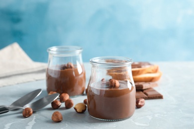 Glass jars with tasty chocolate cream served on table