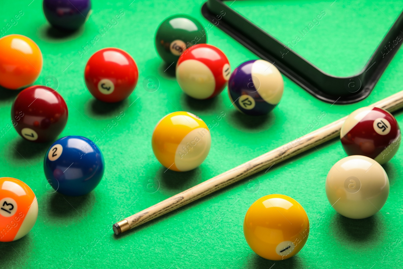 Photo of Many colorful billiard balls and cue on green table