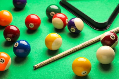 Photo of Many colorful billiard balls and cue on green table