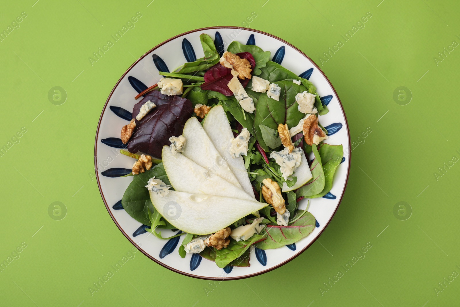 Photo of Delicious pear salad in bowl on green background, top view