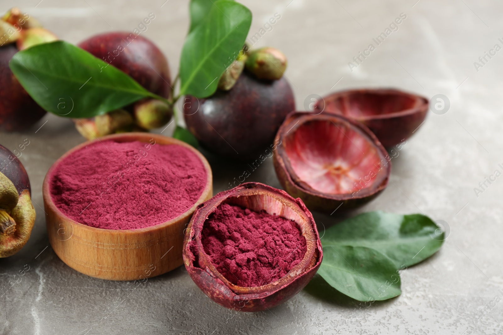 Photo of Purple mangosteen powder and fruits on grey marble table