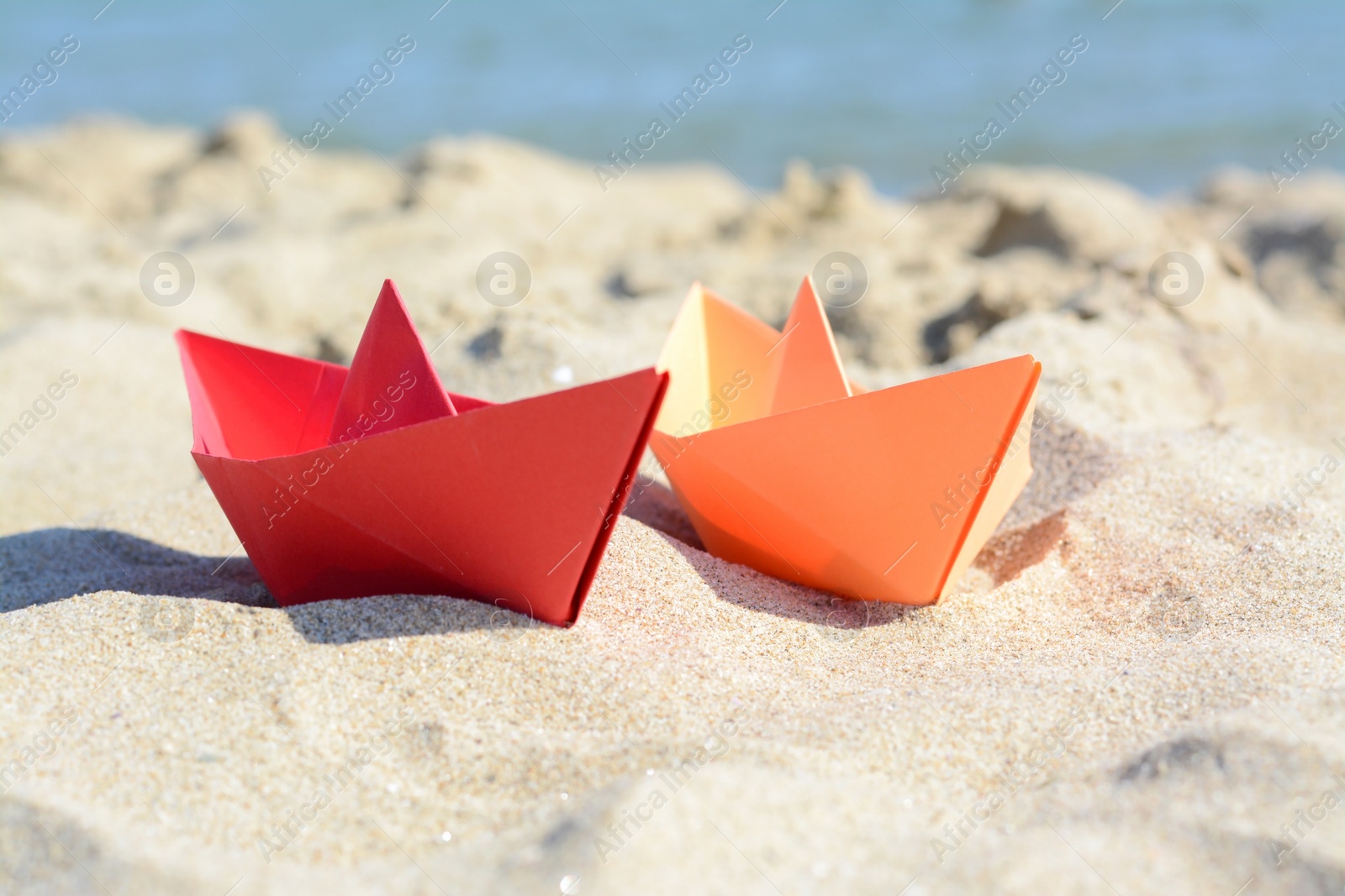 Photo of Two paper boats near sea on sunny day, closeup