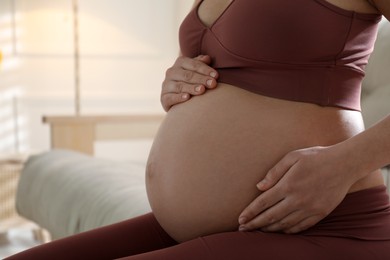 Photo of Pregnant young woman touching belly at home, closeup