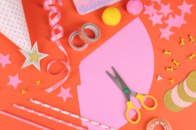 Photo of Different stationery and materials for creation of colorful party hats on orange background, flat lay. Handmade decorations