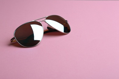 Photo of Stylish sunglasses on pink background, space for text. Fashionable accessory