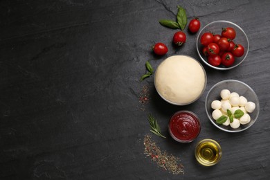 Photo of Raw pizza dough and other ingredients on black table, flat lay. Space for text