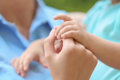 Photo of Young mother holding her child's hand, closeup