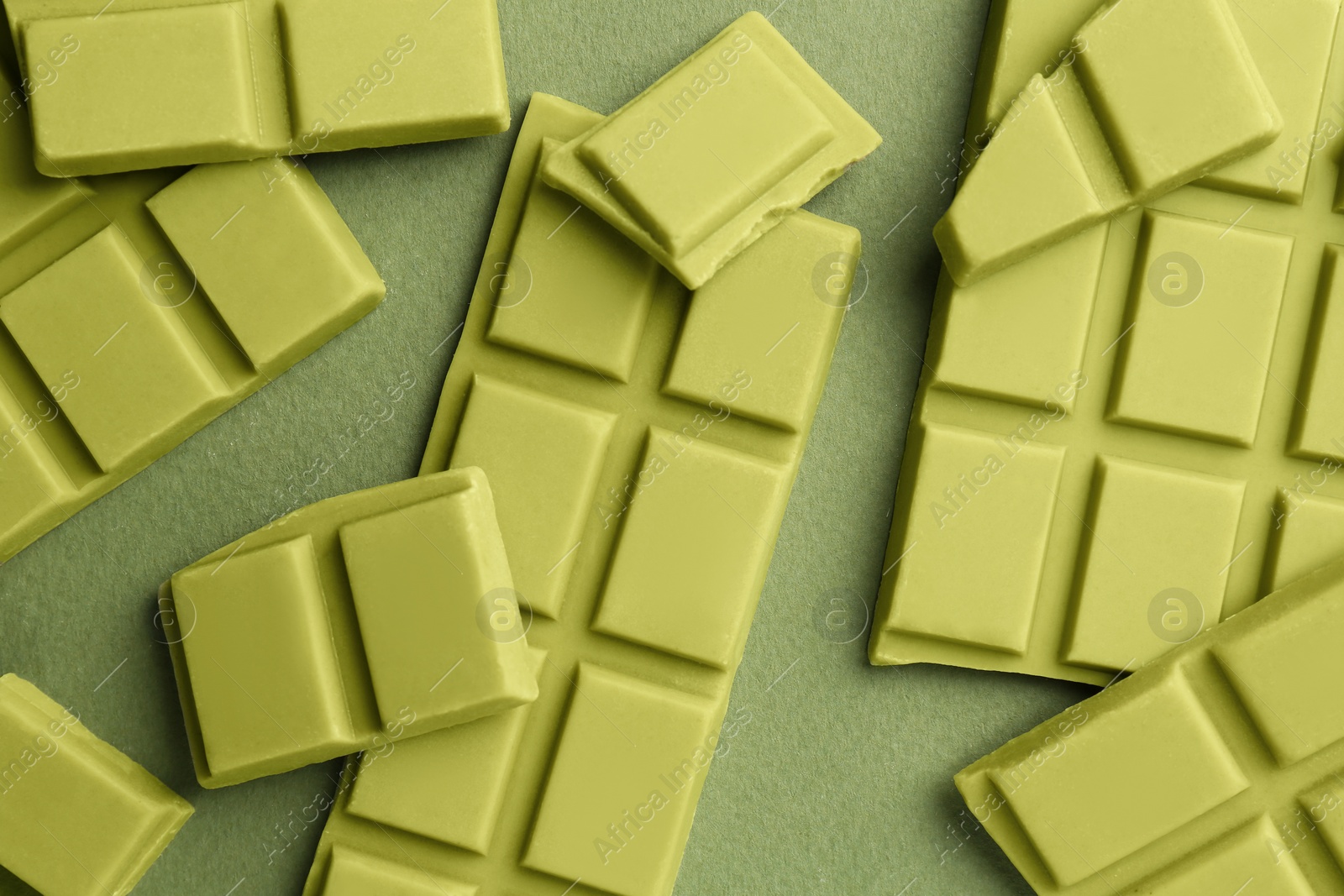 Photo of Pieces of tasty matcha chocolate bars on green background, top view