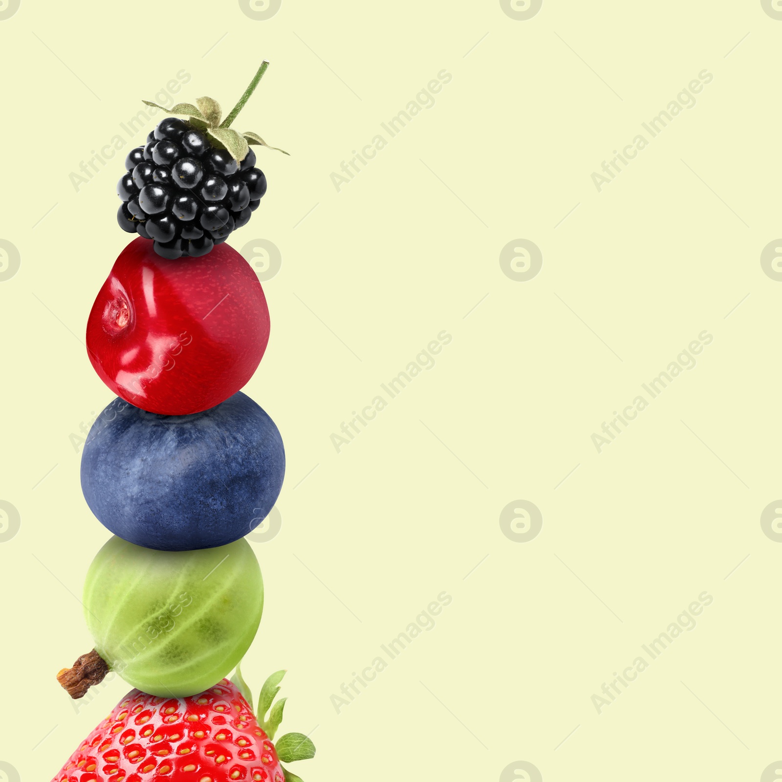 Image of Stack of different fresh tasty berries and cherry on honeydew color background, space for text