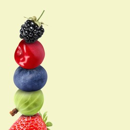 Image of Stack of different fresh tasty berries and cherry on honeydew color background, space for text