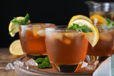 Photo of Delicious iced tea on wooden table against black background