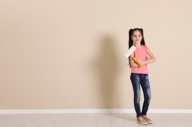 Photo of Child with roller brush near color wall. Space for text