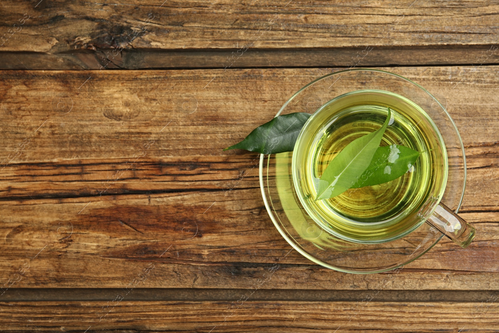 Photo of Cup of aromatic green tea on wooden table, top view. Space for text