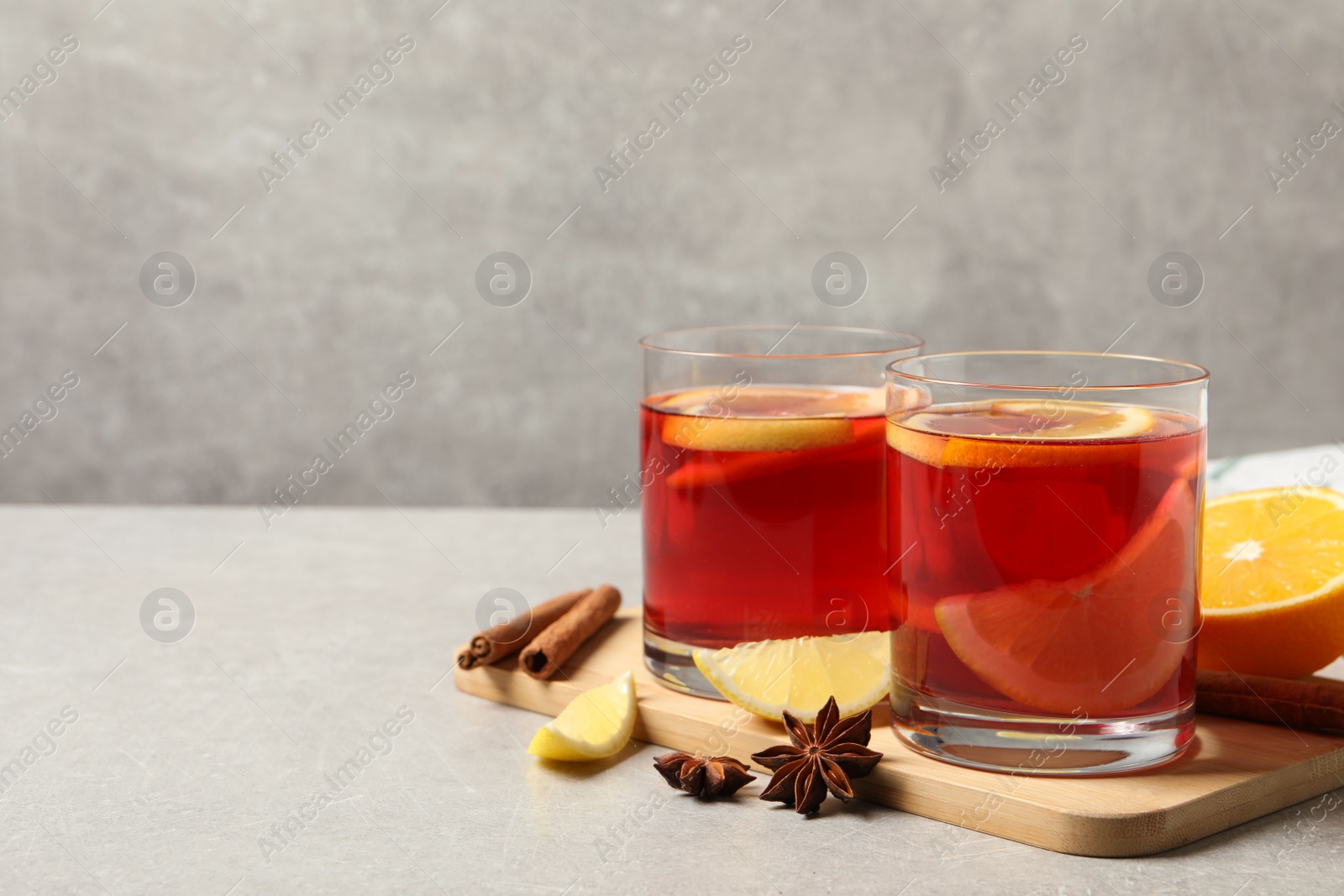 Photo of Aromatic punch drink and ingredients on grey table, space for text