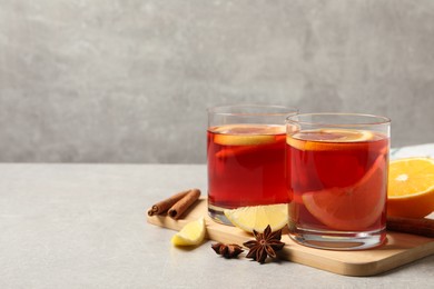Photo of Aromatic punch drink and ingredients on grey table, space for text