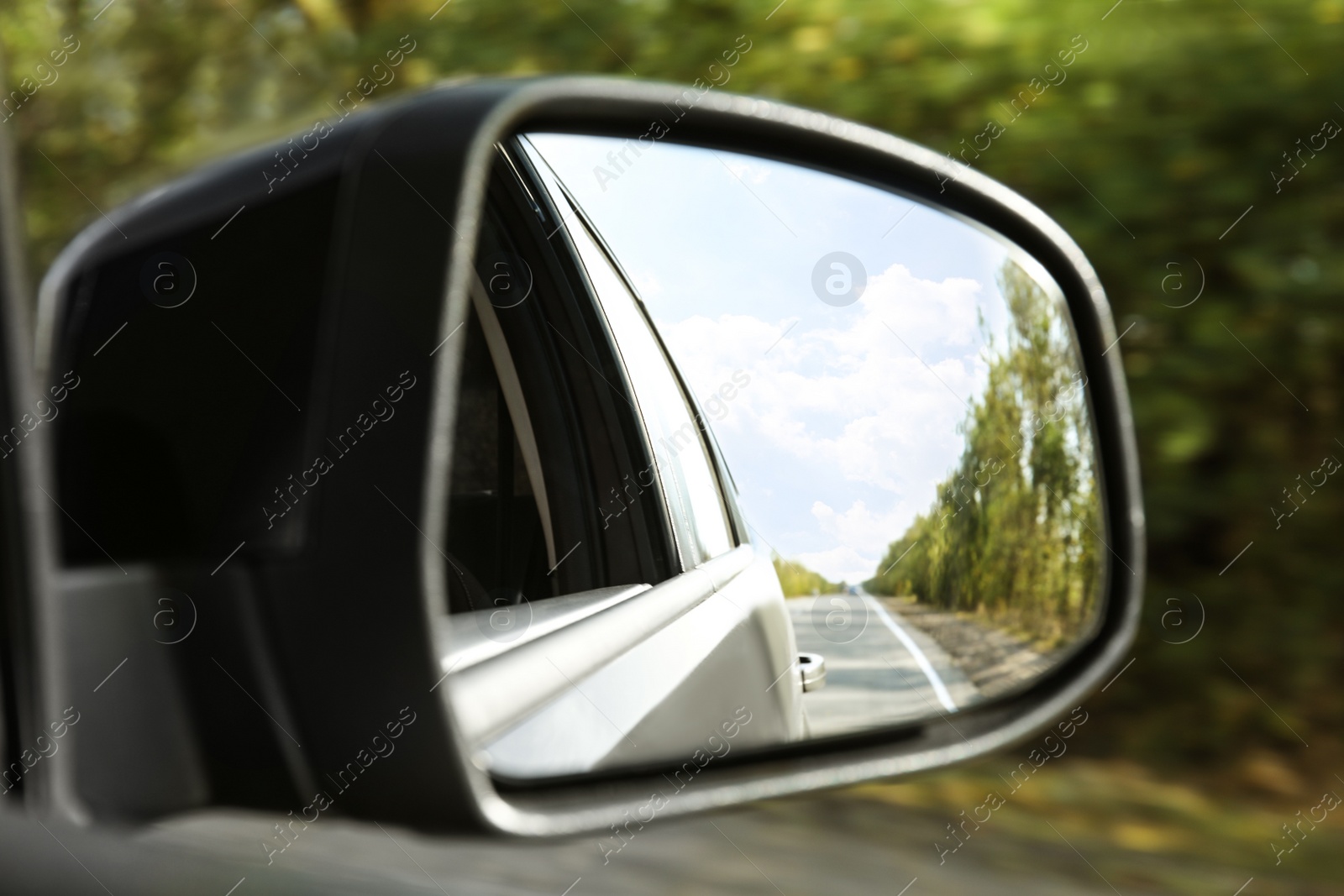 Photo of Closeup of car side rear view mirror on sunny day