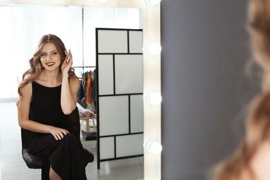 Young beautiful woman near mirror in makeup room