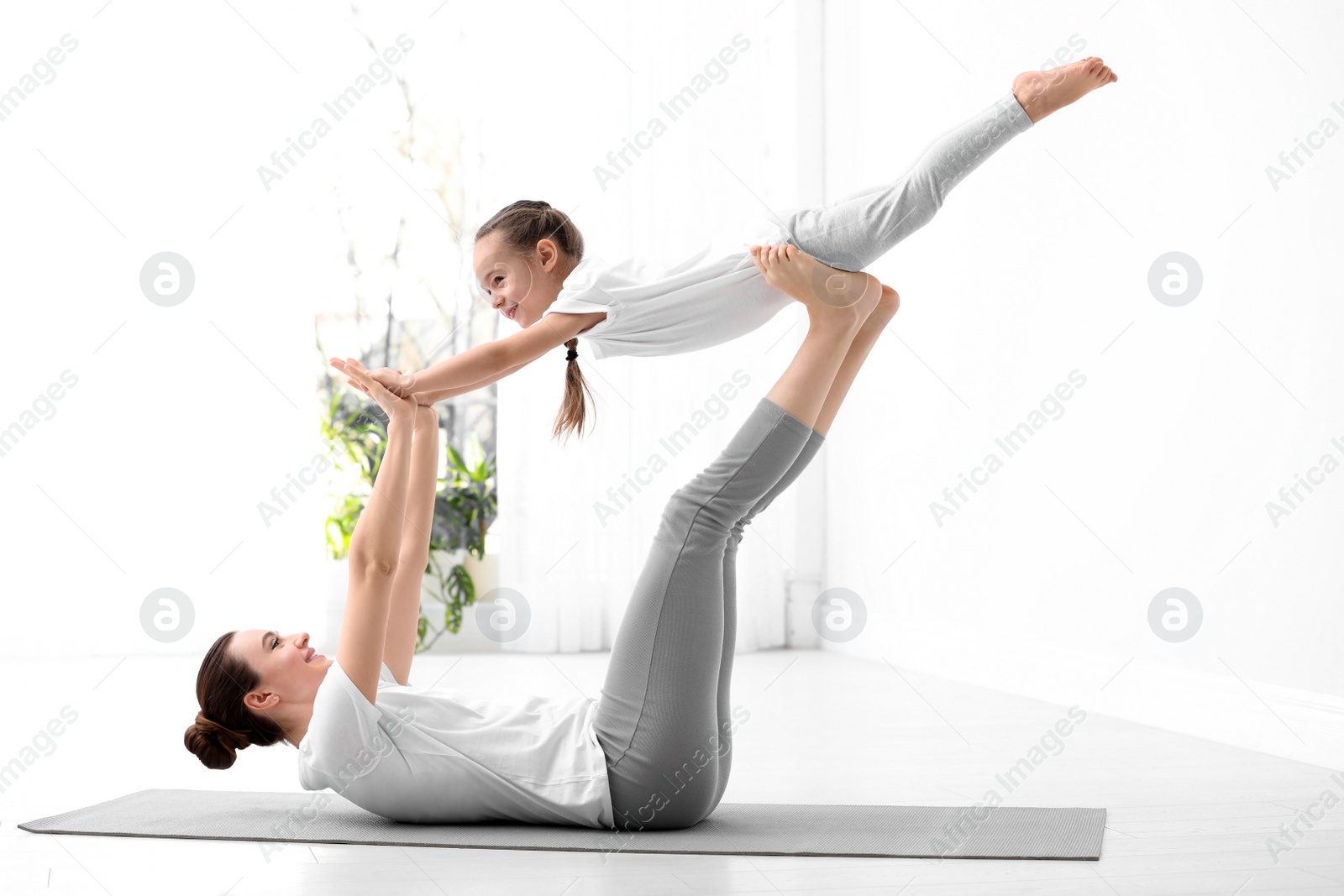 Photo of Young mother with little daughter practicing yoga at home